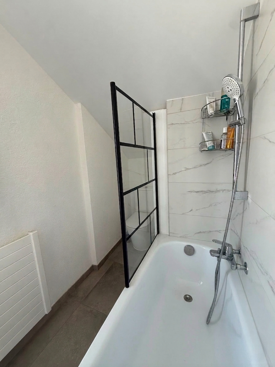 Baignoire avec paroi verrière noire et sol en béton ciré à Lausanne