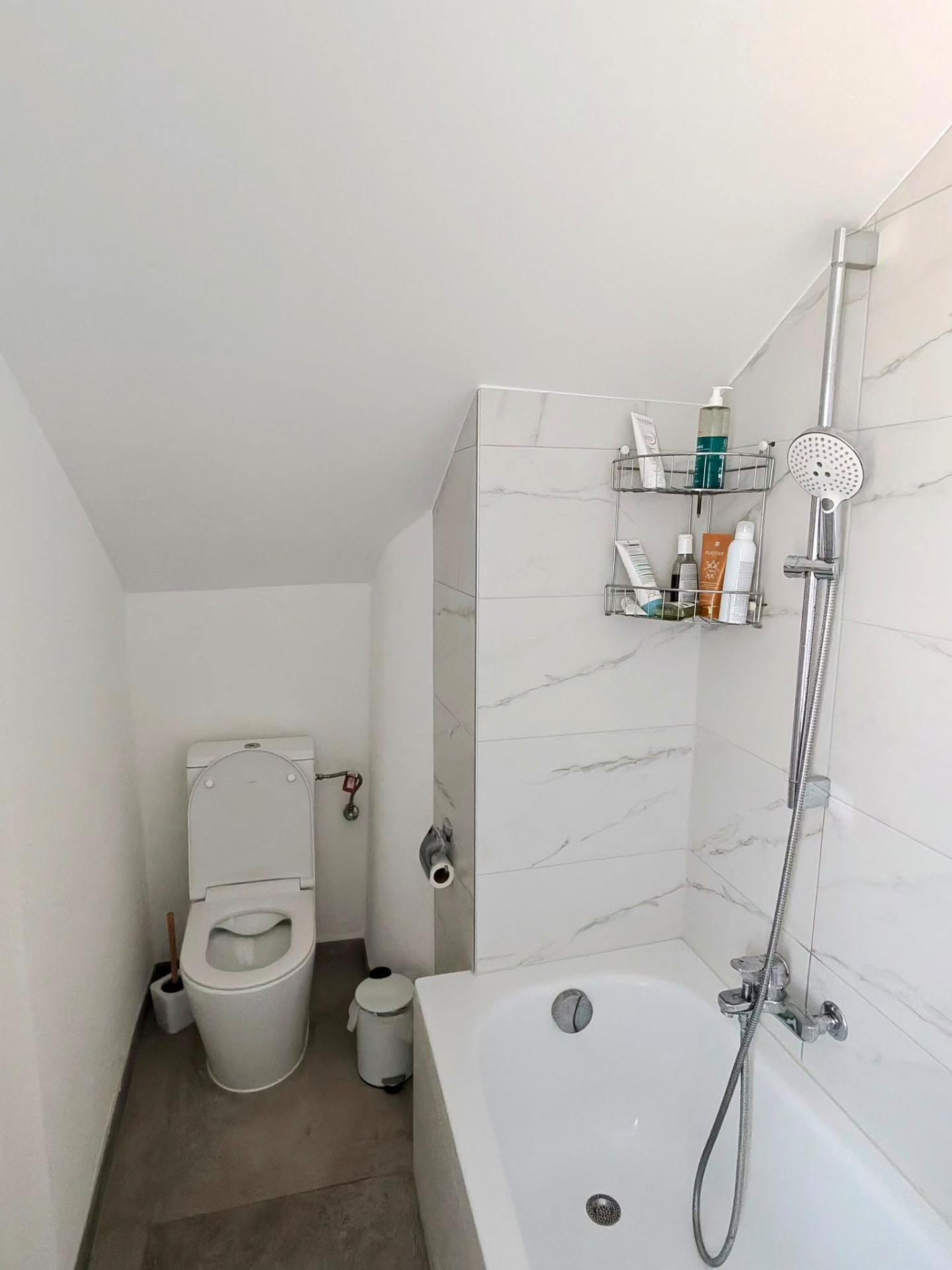 Salle de bain rénovée à Lausanne avec faïence effet marbre, baignoire et WC